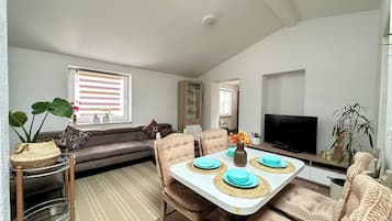 A dining area with a table set for four, a sofa, and a television.