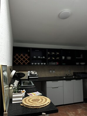 A kitchen with a black countertop, white cabinets, and a microwave. There is a woven placemat on the counter. - Modern apartment that sleeps 6 (Weißenfels)