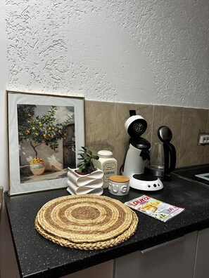 A kitchen counter with a coffee maker, a mug, a framed picture, and a woven placemat. - Modern apartment that sleeps 6 (Weißenfels)