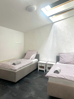A bedroom with two beds, a skylight, and a white textured wall. - Modern apartment that sleeps 6 (Weißenfels)