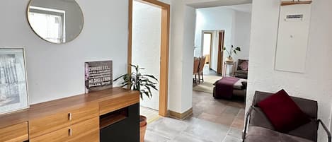 Een moderne receptie met een houten toonbank, een ronde spiegel en een bord met Duitse tekst.