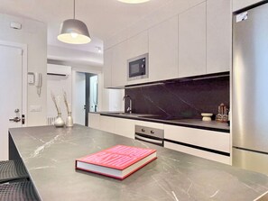 A modern kitchen with a marble countertop, a built-in oven, and a stainless steel refrigerator. - 3-Bedroom Apartment in Salamanca with a Private Terrace (Madrid)