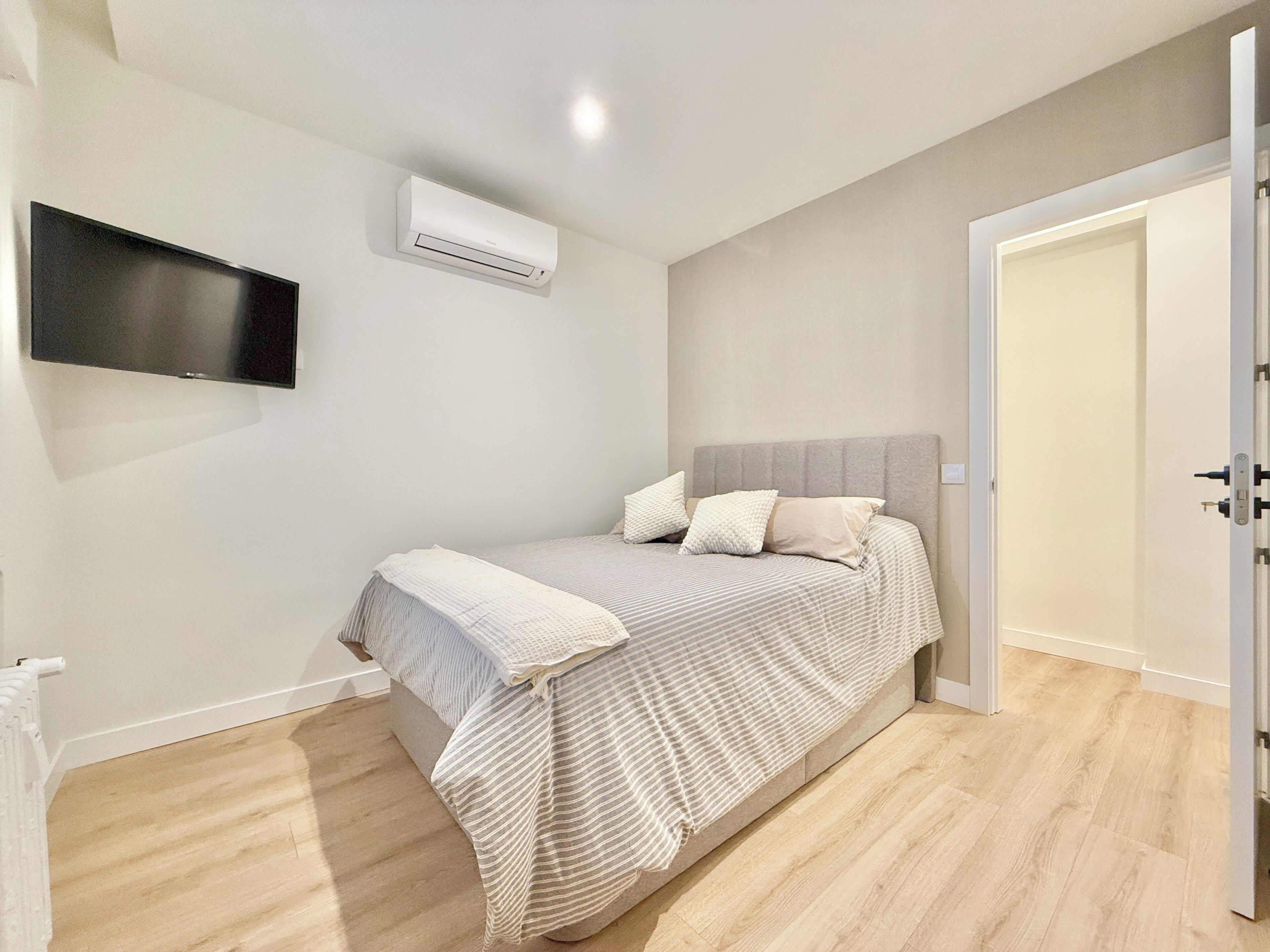 Una camera da letto con un letto, una TV a schermo piatto montata a parete e un condizionatore d'aria.