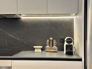 A kitchen with a marble backsplash, a coffee machine, and a set of glassware on the counter. - 3-Bedroom Apartment in Salamanca with a Private Terrace (Madrid)