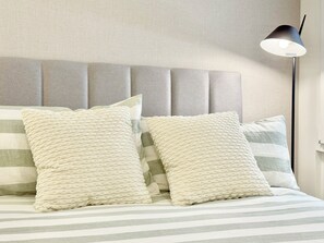 A bed with striped bedding and two textured pillows. - 3-Bedroom Apartment in Salamanca with a Private Terrace (Madrid)