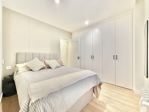 Un dormitorio con cama, armario y mesita de noche.