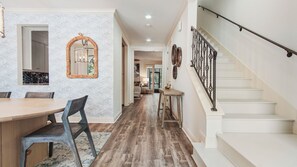 A hallway with a dining area, staircase, and a kitchen visible through an open door. - Santa Rosa Beach luxury 30A townhome near beach, pool, restaurants & relaxation! (Santa Rosa Beach)