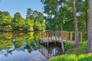 A wooden dock extending over a calm lake surrounded by dense trees.