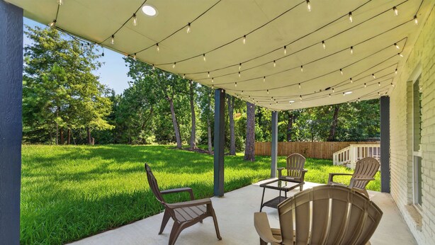 A covered patio area with outdoor furniture and string lights.