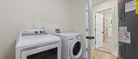 A laundry room with two front-loading washing machines, a dryer, and a refrigerator.