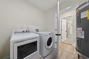 A laundry room with two front-loading washing machines, a dryer, and a refrigerator.