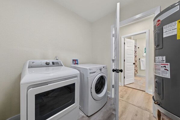 A laundry room with two front-loading washing machines, a dryer, and a refrigerator.