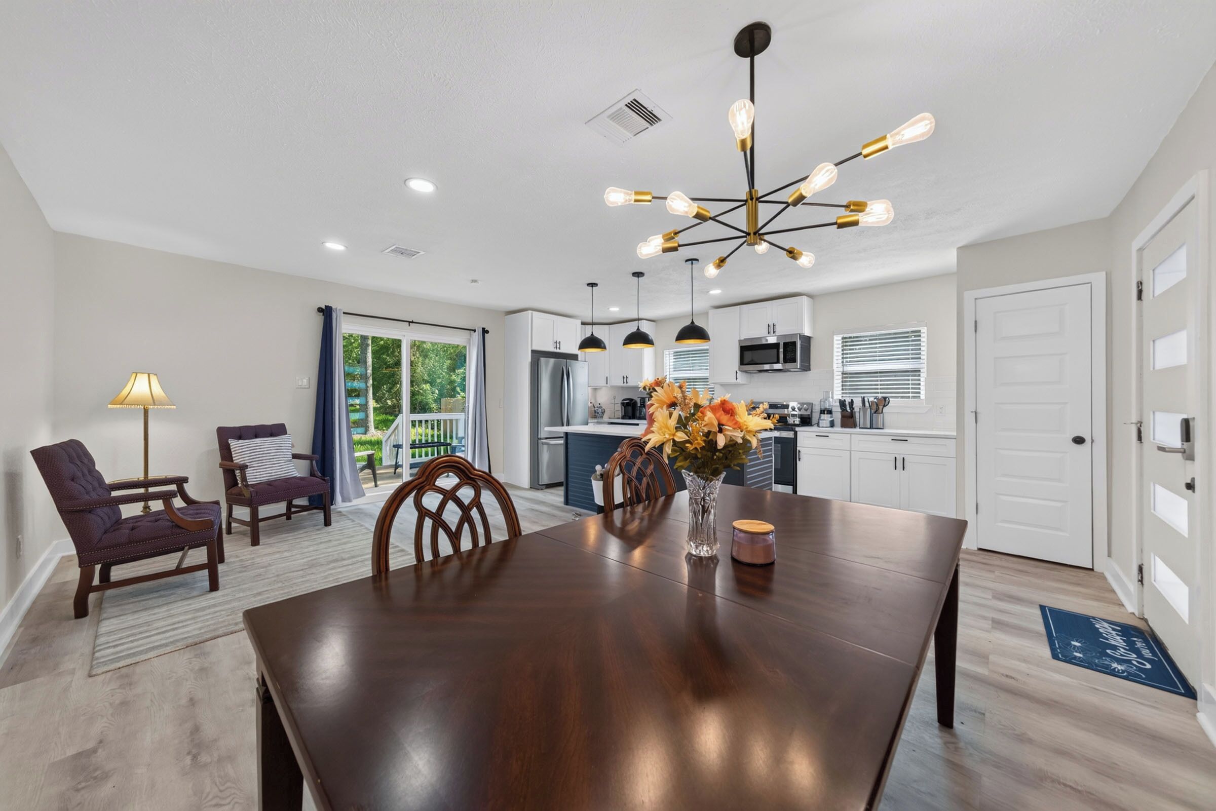 A modern kitchen with white cabinets, stainless steel appliances, and a dining area with a dark wooden table and chairs.