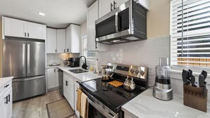 A modern kitchen with stainless steel appliances, white cabinetry, and a black stove.