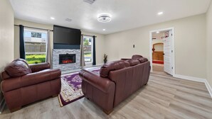 A living room with a fireplace, leather sofas, and a view of the outdoors.