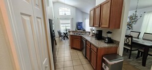 A kitchen with wooden cabinets, a coffee maker, a blender, and a trash bin. - Luxury Disney Vacation Home Private Pool Resort Amenities Sleeps 8 Game Room (Kissimmee)