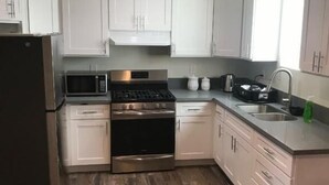 Une cuisine moderne avec des armoires blanches, des appareils en acier inoxydable et un plancher en bois.