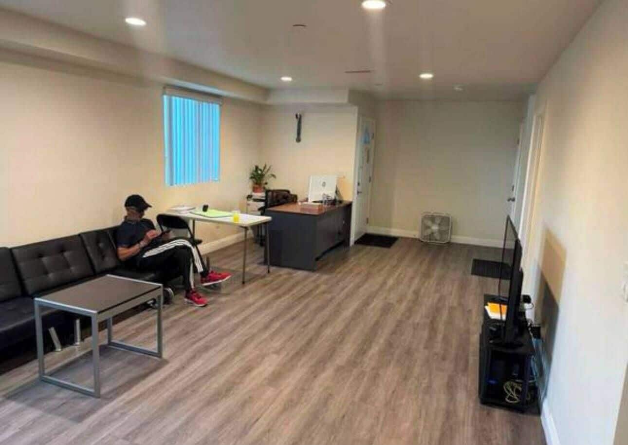 A living room with a sofa, a coffee table, a TV stand, and a desk.
