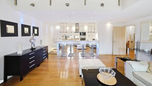Een modern interieur met een eethoek, keuken en een trap naar een hoger gelegen verdieping.