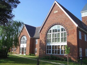 A large brick building with a prominent arched window and a smaller arched entrance. - Luxury 3-Bed Penthouse · Sleeps 7 · Gated · NEC (Shirley)