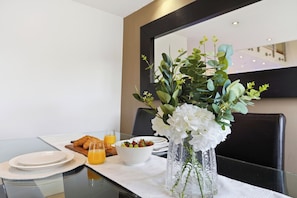 A breakfast setting with croissants, a bowl of fruit, and a glass of orange juice on a table with a white tablecloth. - Luxury 3-Bed Penthouse · Sleeps 7 · Gated · NEC (Shirley)
