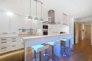 Una cocina moderna con una isla central, taburetes de bar e iluminación colgante.