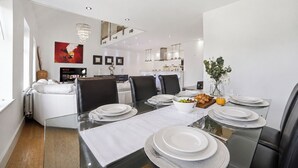 Een moderne eethoek met een glazen tafel, witte borden en een bloevas.