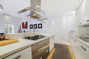 A modern kitchen with a gas stove, stainless steel appliances, and a sleek design. - Luxury 3-Bed Penthouse · Sleeps 7 · Gated · NEC (Shirley)