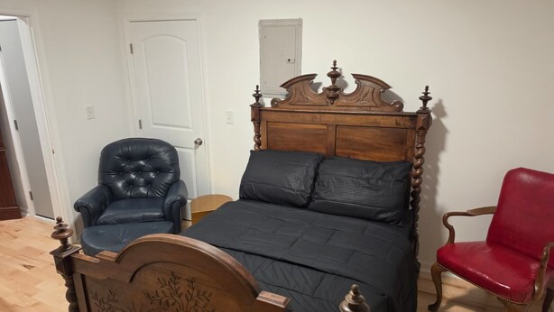 Ein Schlafzimmer mit einem hölzernen Bett, einem Ledersessel und einem roten Stuhl.