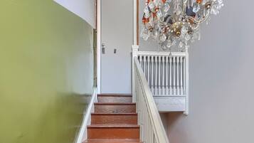 A staircase with a white railing, a door with a keypad lock, and a chandelier with crystal decorations.