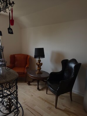 A room with a round table, two chairs, a lamp, and kitchen utensils on the wall.