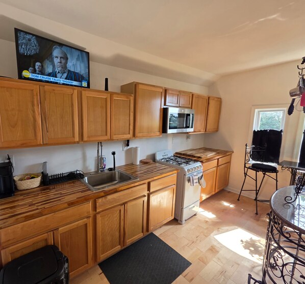 A kitchen with wooden cabinets, a stainless steel oven, a microwave, and a gas stove.