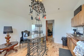 A spacious living area with a dining table, a chair, a lamp, and a kitchen area with cabinets and a stove.
