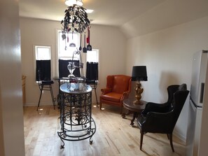 A dining area with a round table, chairs, a chandelier, and a window with curtains.