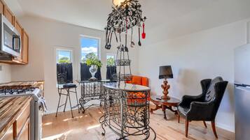 A kitchen with a stove, a dining table with chairs, a chandelier, and a refrigerator.