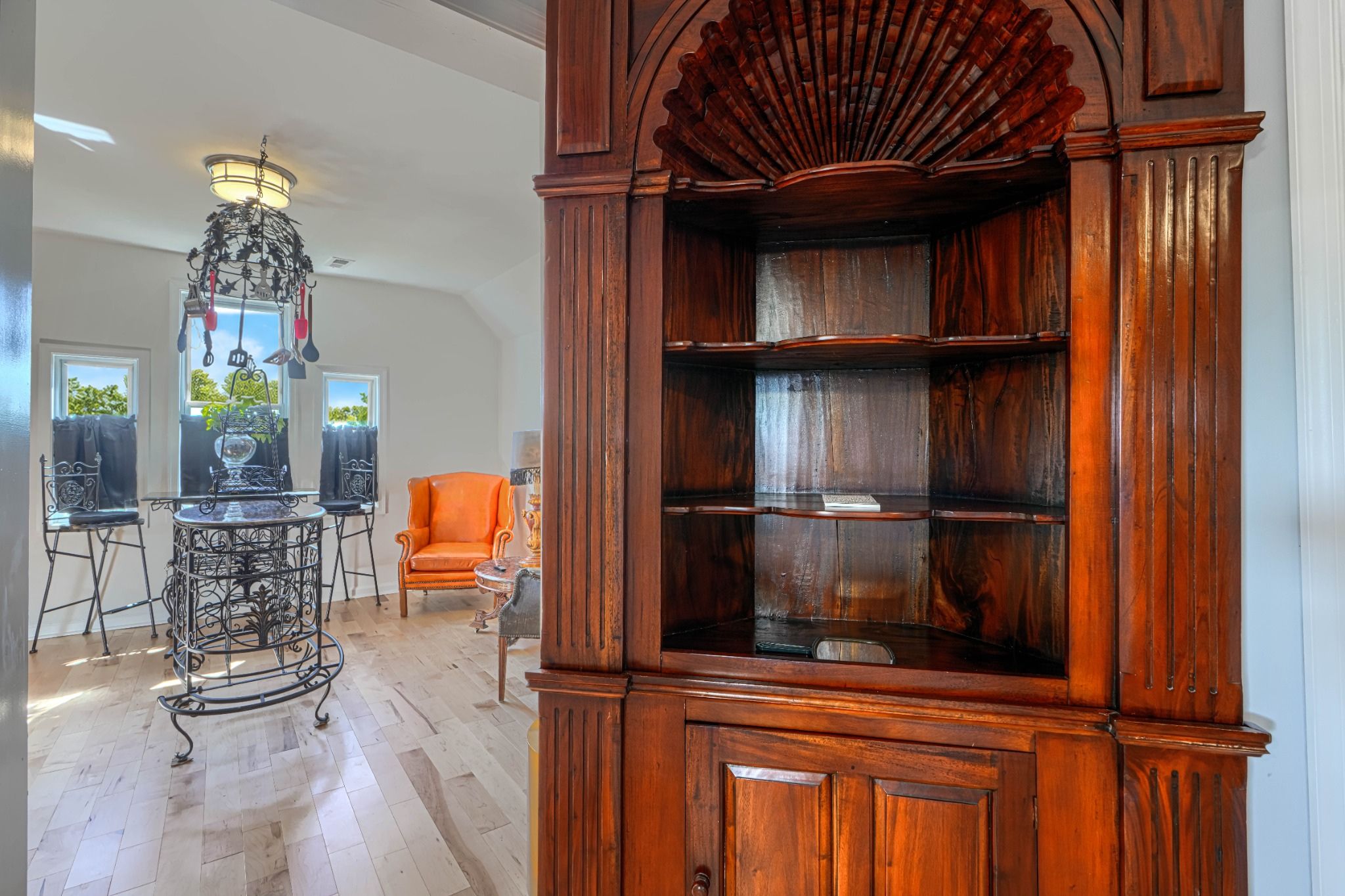Une pièce comprenant un buffet en bois, un lustre en métal et un coin repas avec une table et des chaises.