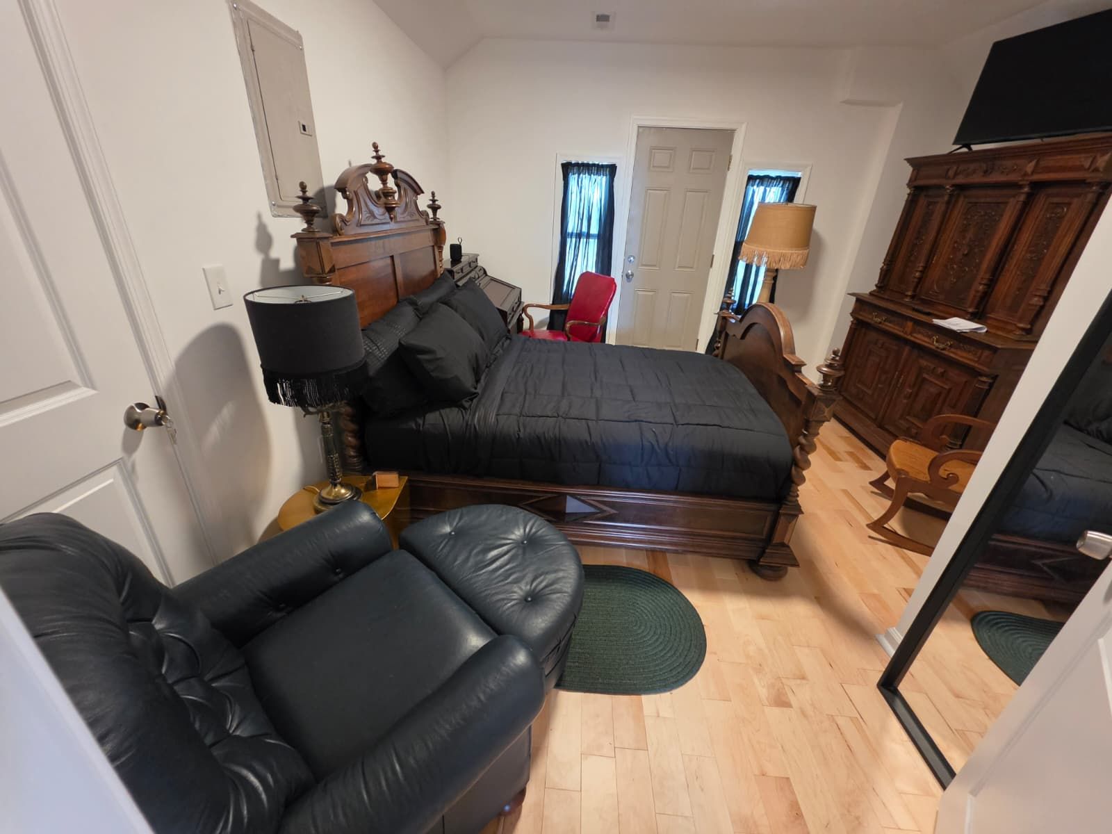 Ein Schlafzimmer mit Bett, Stuhl, Kommode und Spiegel.