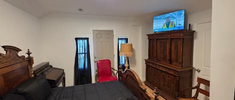 A hotel room with a bed, a television, a wooden cabinet, a chair, and a desk.