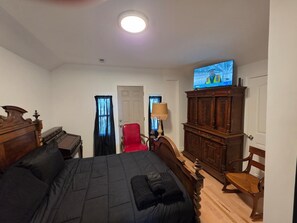 A hotel room with a bed, a television, a wooden cabinet, a chair, and a desk.