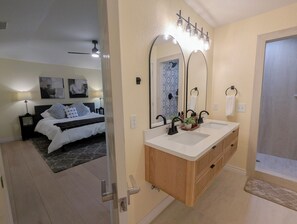 A modern bathroom with a double sink vanity, a large mirror, and a shower area. - Newly Renovated 3BR+Sunroom, Sleeps 8. Walk to Downtown McKinney & Finch Park (McKinney)