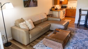 En moderne stue med sofa, sofabord og et maleri af en strand.