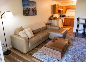 Ein modernes Wohnzimmer mit einer Couch, einem Couchtisch und einem Gemälde mit einer Strandansicht.