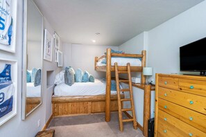 A bunk bed with a ladder, a television, and a wooden dresser in a room with framed pictures on the wall. - Scenic Mountain Village Stay - Hot Tub , Gym (Mountain Village)