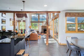 Una cocina moderna con una isla central, un comedor con mesa redonda y una chimenea.