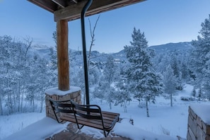 A wooden bench under a covered area with a stone wall, overlooking a snow-covered landscape with trees and distant mountains. - Scenic Mountain Village Stay - Hot Tub , Gym (Mountain Village)