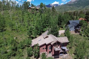 Ein großes, mehrstöckiges Blockhaus mit einem markanten Balkon und Blick auf die Berge.