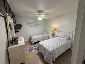 A bedroom with two beds, a ceiling fan, a TV, and a bedside lamp. - Ocean Front 2-bedroom condo in beautiful St Thomas (St Thomas)