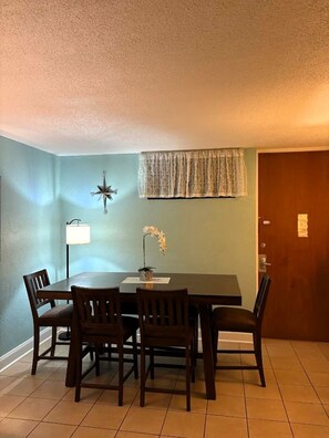 A dining area with a table and chairs, a wall-mounted lamp, a decorative item, and a door. - Ocean Front 2-bedroom condo in beautiful St Thomas (St Thomas)