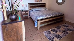 A bedroom with a bed, a nightstand, a dresser, a ceiling fan, and a wall-mounted mirror. - Ocean Front 2-bedroom condo in beautiful St Thomas (St Thomas)