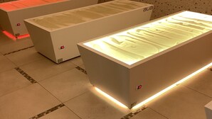 Tres vitrinas rectangulares e iluminadas con el nombre de marca 'alia', sobre un piso de baldosas y un fondo con un papel tapiz estampado.